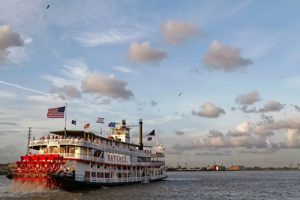 Steamboat Natchez paddlewheeler cruising the Mississippi River under a cloudy evening sky