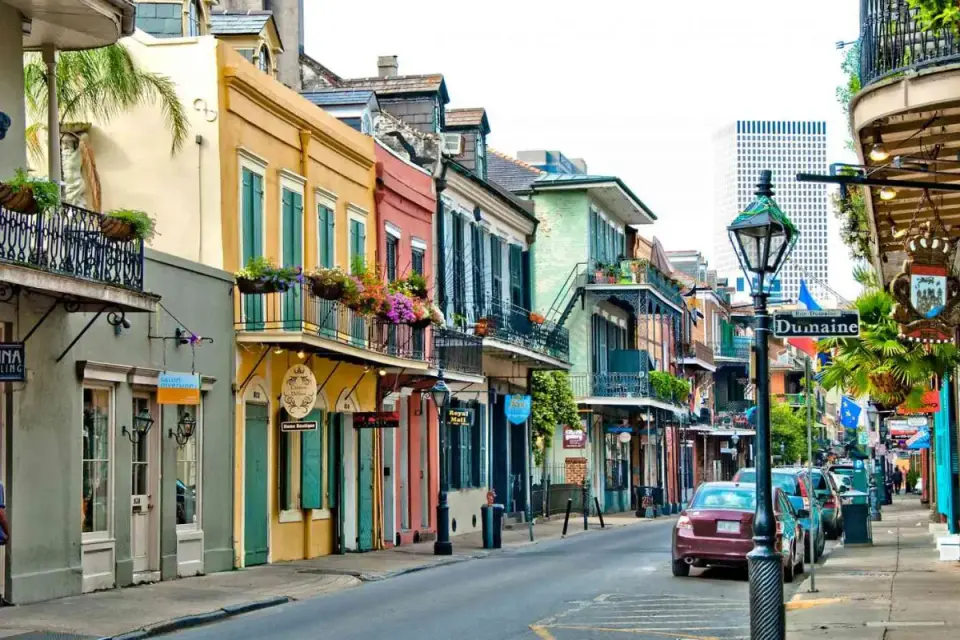 Colorful French Quarter street lined with balconied Creole townhouses at Dumaine Street corner