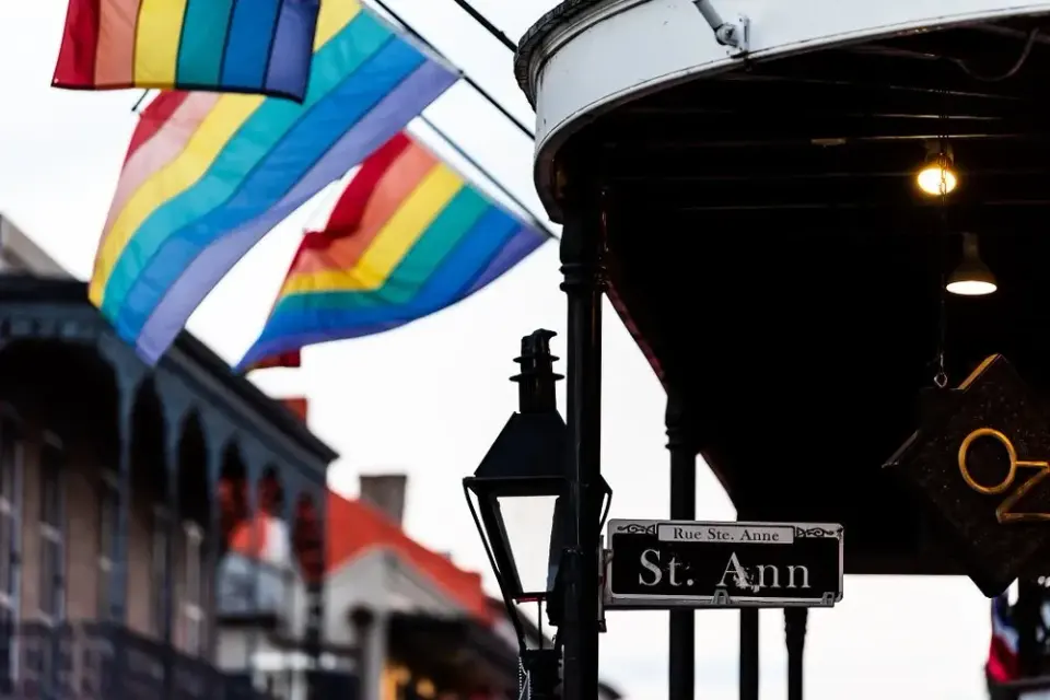 Rainbow pride flags waving beside the St. Ann street sign in New Orleans' French Quarter
