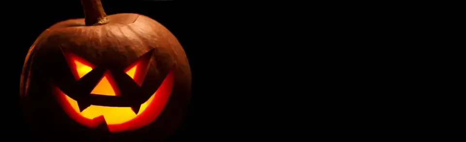 Glowing carved jack-o'-lantern with a menacing grin set against a black background