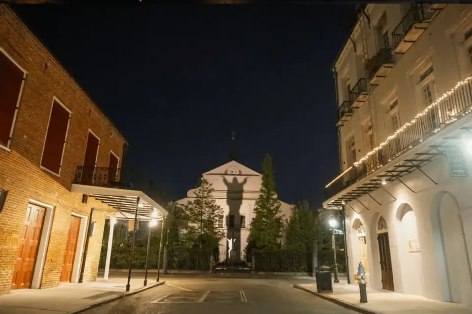 Deserted French Quarter street at night with a ghostly shadow cast on a distant building