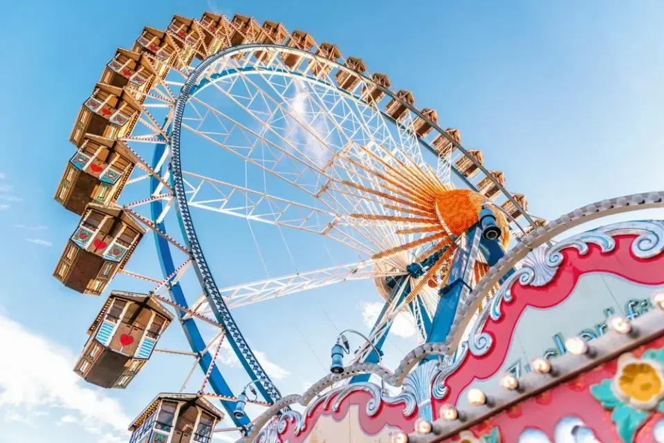 Towering carnival Ferris wheel with vintage gondolas against a bright blue sky at a fair