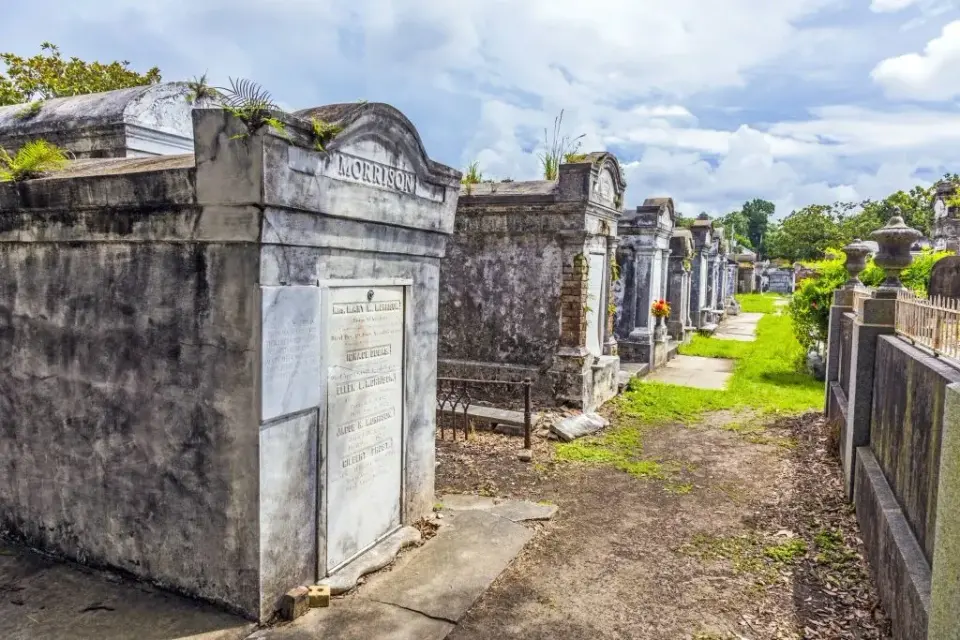 Rows of weathered above-ground stone tombs and mausoleums in a historic New Orleans cemetery