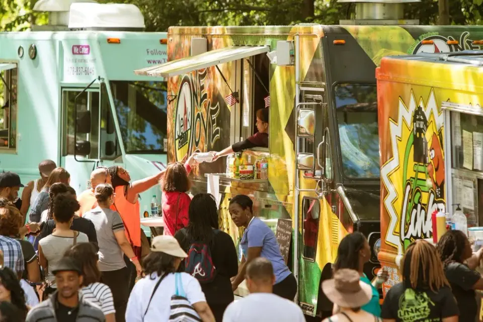 Crowd lining up at colorful street food trucks serving meals at an outdoor festival